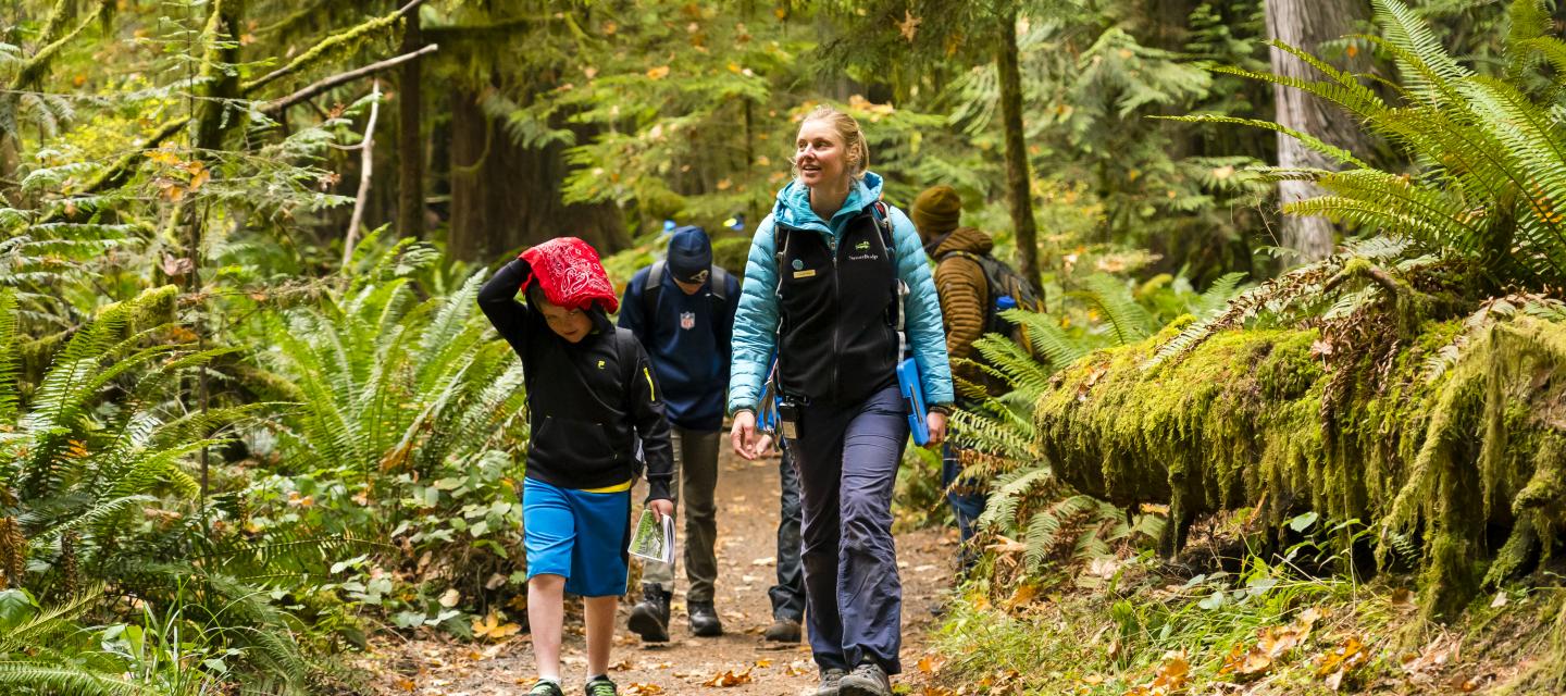 An educator leads students through the Olympic National Park forest.